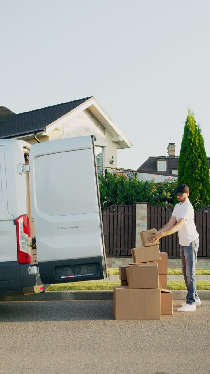 gallery-3 A delivery man organizing packages into a van outside a suburban house.