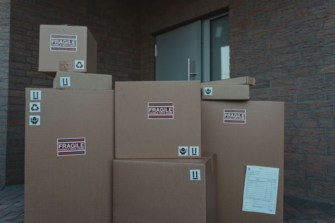 gallery-4 Several cardboard packages marked as fragile stacked at a building entrance.